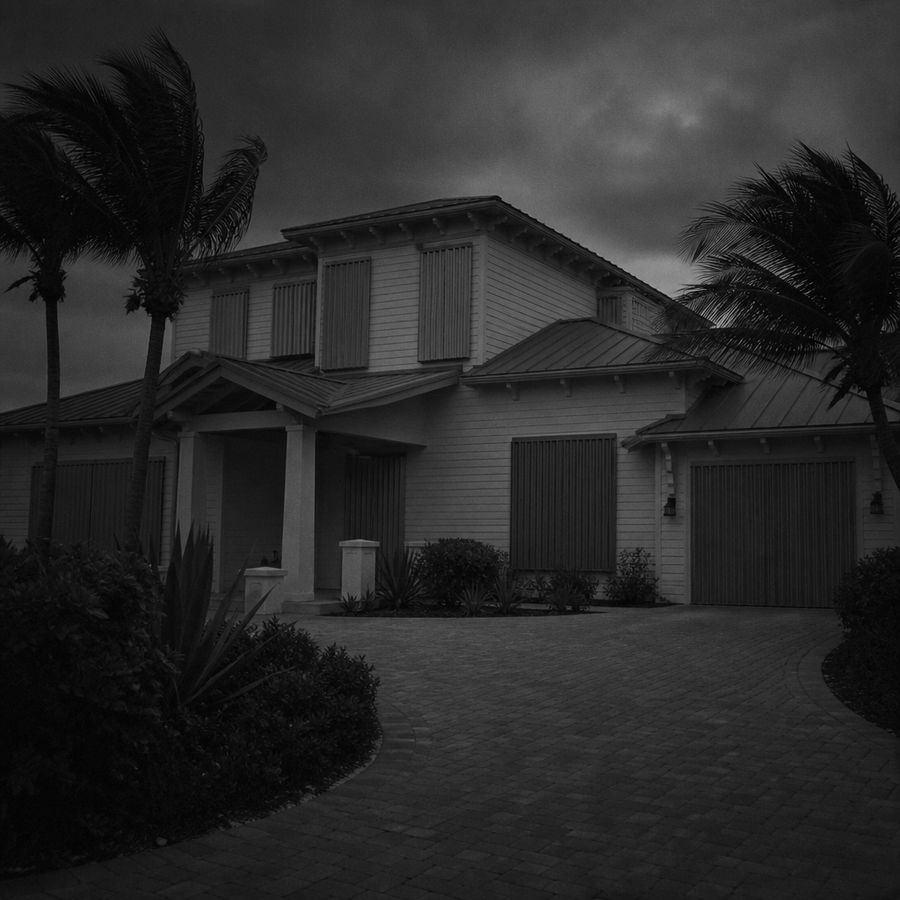 A Florida house closed up behind storm shutters at dusk